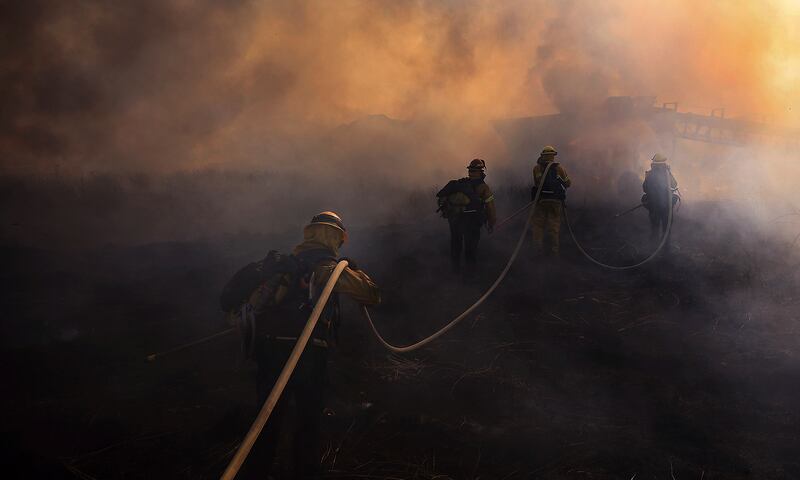 Thick, acrid smoke envelops firefighters as they battle a brush and timber slash fire north of Ukiah, California.