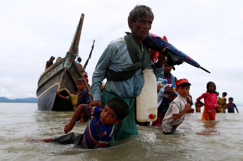 A Rohingya refugee man pulls a child as they walk to the shore after crossing the Bangladesh-Myanmar border by boat through the Bay of Bengal in Shah Porir Dwip, Bangladesh, September 10, 2017. REUTERS/Danish Siddiqui     TPX IMAGES OF THE DAY