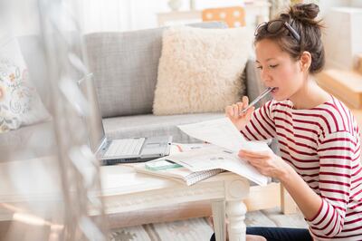 Mixed race woman paying bills on laptop. Getty Images