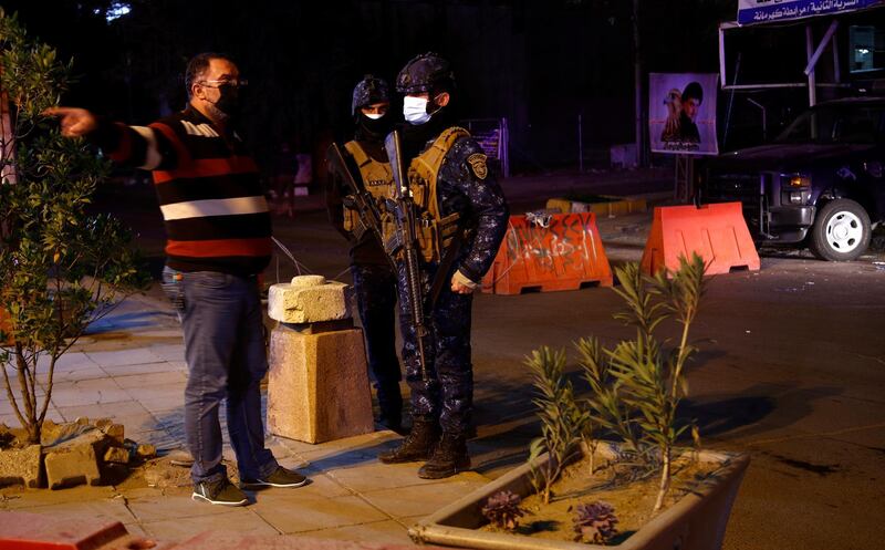 Police question a civilian in Baghdad after the start of the new curfew to prevent the spread of Covid-19. AP Photo