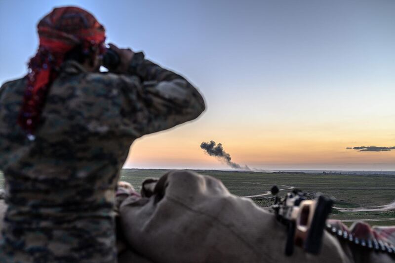 A Syrian Democratic Forces fighter uses a binocular to inspect the embattled village of Baghouz in Syria. AFP