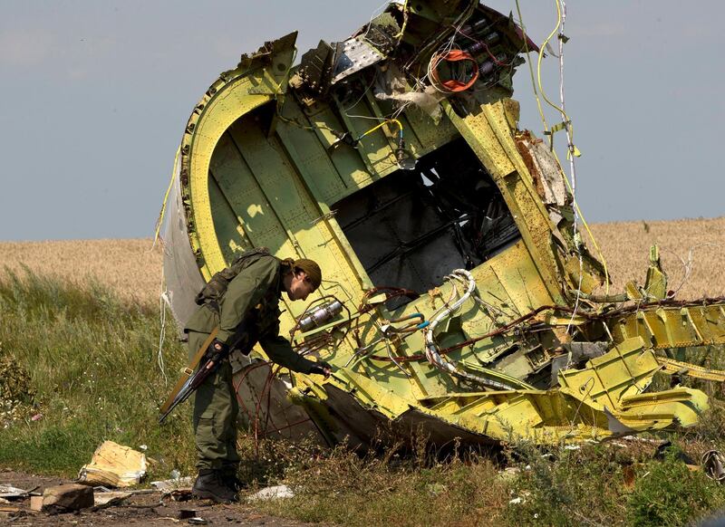 In this July 22, 2014 file photo, a rebel fighter touches the MH17 wreckage at the crash site of Malaysia Airlines Flight 17, near the village of Hrabove, eastern Ukraine. AP Photo