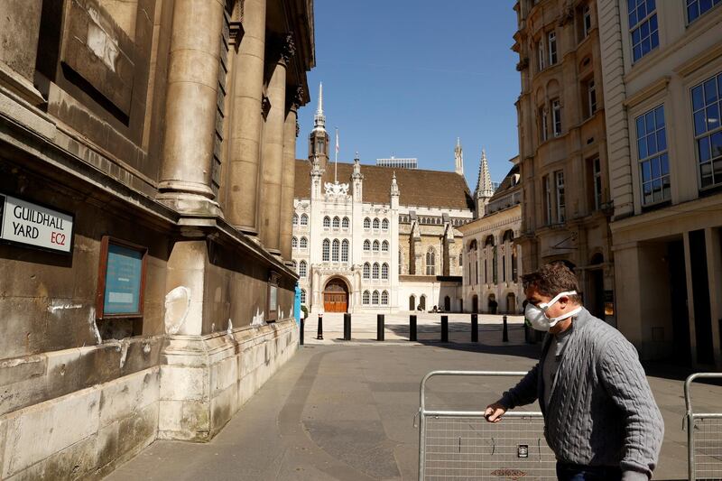 FILE PHOTO: A man wearing a mask outside Guildhall in the city of London as the spread of the coronavirus disease (COVID-19) continues, London, Britain, April 14, 2020. REUTERS/John Sibley/File Photo