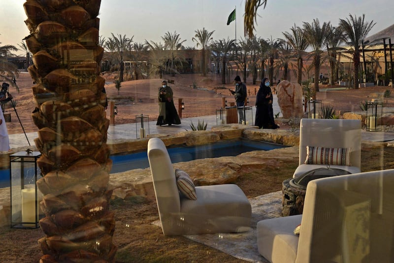 Visitors walk by a water canal beneath palm trees at the "Riyadh Oasis." AFP