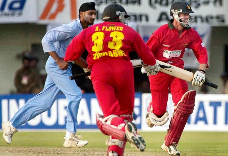 Zimbabwe's batsmen Andy Flower (M) and Grant Flower (R) run as Indian bowler Harbhajan Singh (L) looks on during the fourth one-day international between India and Zimbabwe at Lal Bahadur Shastri stadium in Hyderabad, 16 March 2002.  Andy Flower scored 89 runs as Zimbabwe was 240 for eight. AFP PHOTO/RAVEENDRAN (Photo by RAVI RAVEENDRAN / AFP)