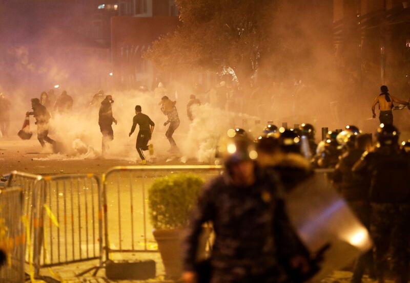 Anti-government protesters run away as the riot police fire tear gas at them during a protest in central Beirut. AP Photo