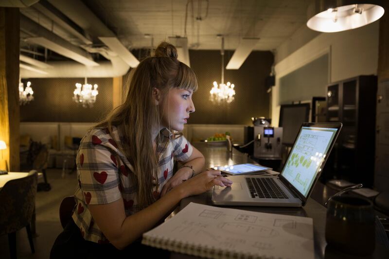 Focused female designer working late at laptop in office