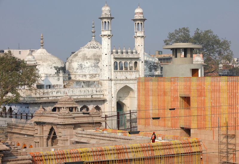 A worker stands on a temple rooftop adjacent to the Gyanvapi Mosque. Reuters