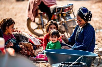 A Syrian woman, displaced from Ras al-Ain, a border town controlled by Turkey and its Syrian proxies, amuses a child as others look on in the camp of Washokani in the northeastern Syrian al-Hasakeh governorate, on November 12, 2020.   / AFP / Delil SOULEIMAN
