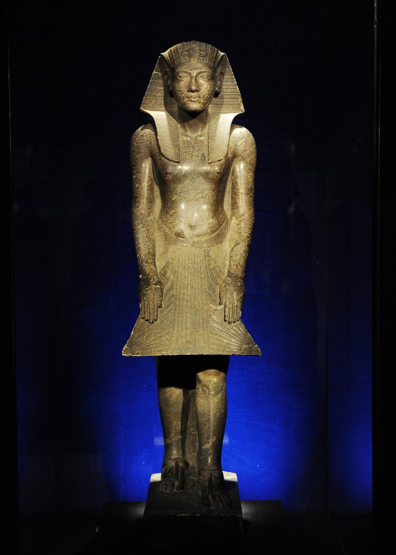 Detail of a granite statue of Tutankhamun on display April 21, 2010 at a preview of "Tutankhamun and the Golden Age of the Pharaohs", an exhibition at Discovery Times Square Exposition in New York. Multicolored medical scans of the real mummy are reflected in the glass case. The exhibit opens April 23. AFP PHOTO/Stan Honda (Photo by STAN HONDA / AFP)