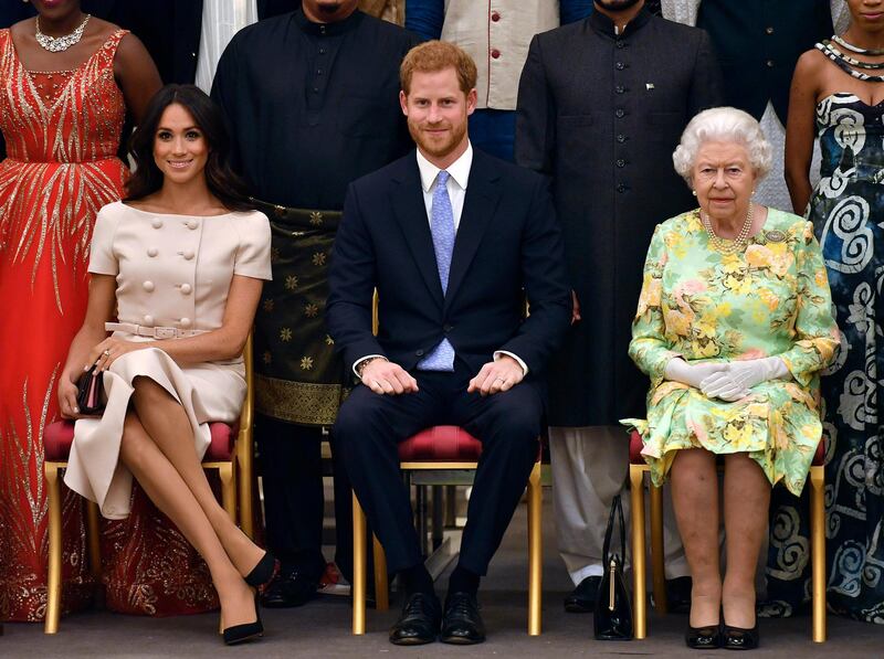 FILE - In this Tuesday, June 26, 2018 file photo, Britain's Queen Elizabeth, Prince Harry and Meghan, Duchess of Sussex pose for a group photo at the Queen's Young Leaders Awards Ceremony at Buckingham Palace in London. As part of a surprise announcement distancing themselves from the British royal family, Prince Harry and his wife Meghan declared they will â€œwork to become financially independentâ€ _ a move that has not been clearly spelled out and could be fraught with obstacles.(John Stillwell/Pool Photo via AP, File)