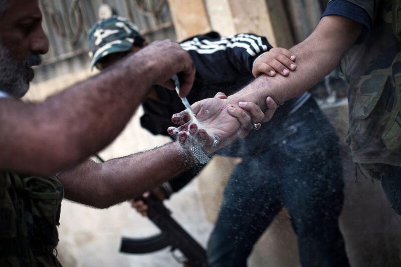 A soldier helps a comrade treat his hand after he was wounded by a sniper in Izaa district.  Manu Brabo / AP Photo
