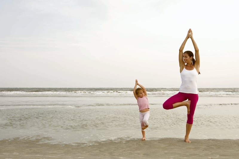 Woman enjoying peaceful yoga exercise on beach with daughter. Carolina.  Evening light.  