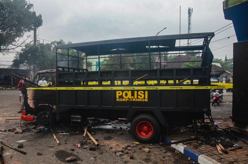 People walk past a torched police truck outside Kanjuruhan Stadium. EPA