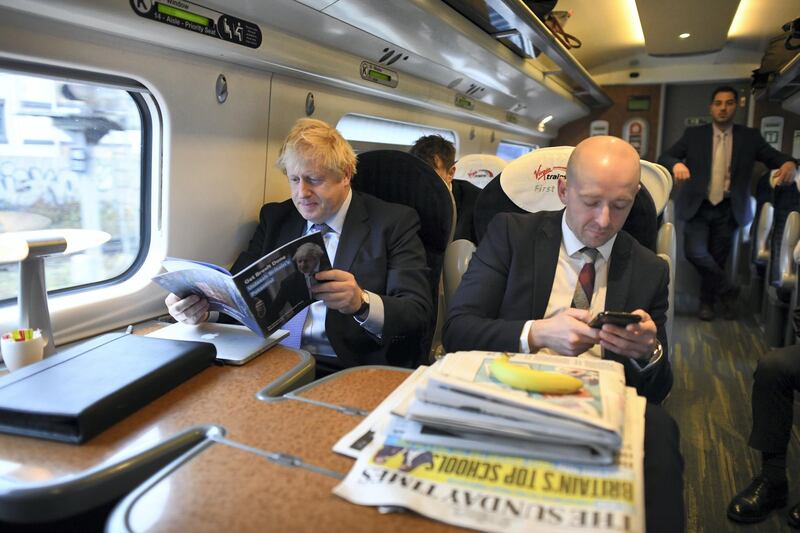 Prime Minister Boris Johnson, sitting with his Director of Communications, Lee Cain (right), looks over his party's manifesto as he heads by train to Telford for its launch at the Telford International Centre in Telford, West Midlands. (Photo by Stefan Rousseau/PA Images via Getty Images)