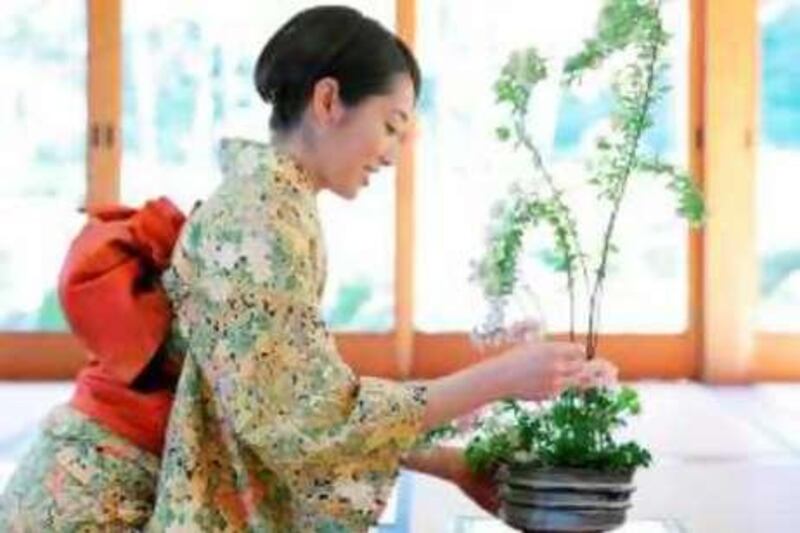Asian Woman Caring for Flowers --- Image by © Bloomimage/Corbis