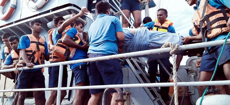 An injured crew member is transferred on stretcher to a navy vessel. AP