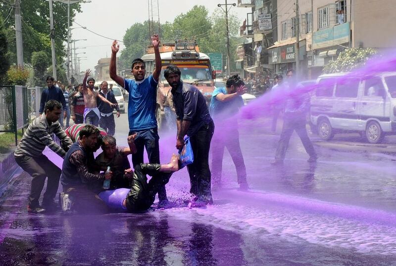 Kashmiri government employees demonstrate as riot police spray purple-dyed water cannon during a protest in Srinagar, India.  Rouf Bhat / AFP

