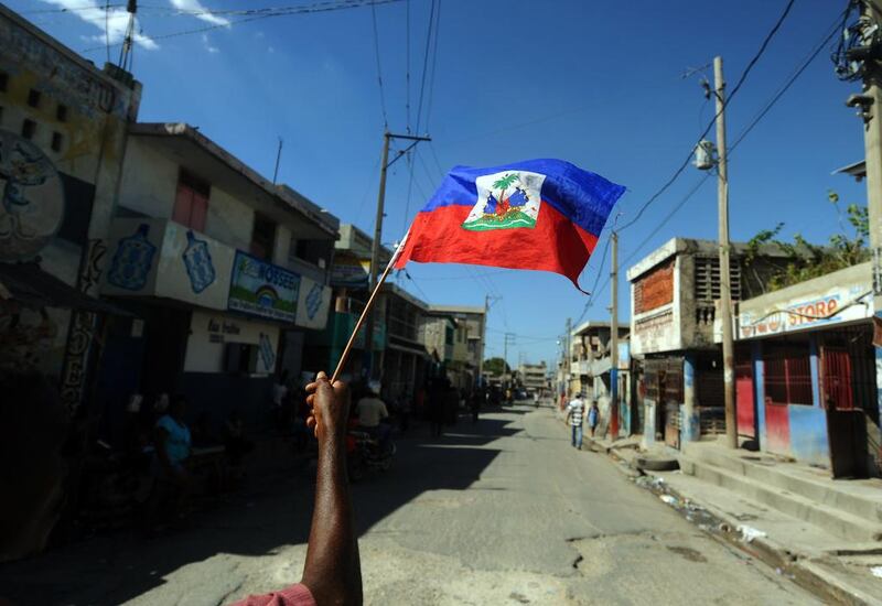 TSA man holds a Haitian flag as he takes part in a protest demanding that Haitian President Michel Martelly steps down in Port-au-Prince. Hector Retamel / AFP Photo