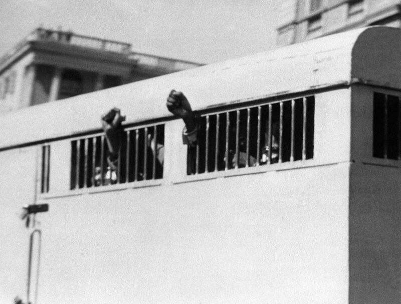 June 16, 1964: A pictures shows eight men, among them Nelson Mandela, sentenced to life imprisonment in the Rivonia trial leaving the Palace of Justice in Pretoria with their fists raised in defiance through the barred windows of the prison car. AFP