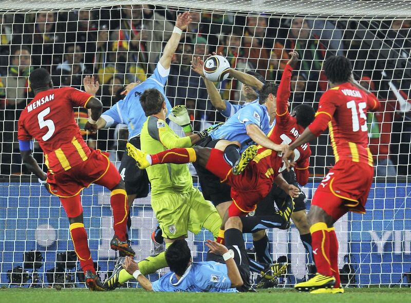 JOHANNESBURG, SOUTH AFRICA - JULY 02:  Dominic Adiyiah of Ghana heads the ball towards goal and Luis Suarez of Uruguay handles the ball off the line during the 2010 FIFA World Cup South Africa Quarter Final match between Uruguay and Ghana at the Soccer City stadium on July 2, 2010 in Johannesburg, South Africa.  (Photo by Paul Gilham - FIFA/FIFA via Getty Images)