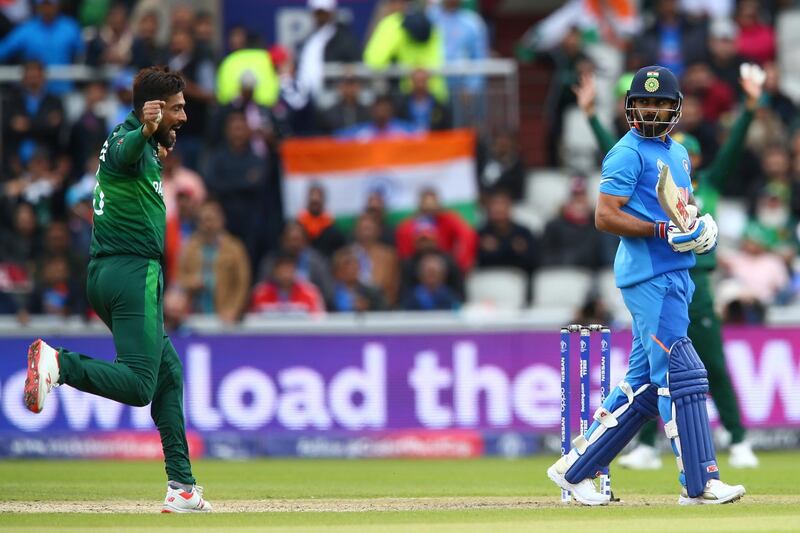 India's captain Virat Kohli, right, leaves the pitch after he is caught by Pakistan's captain Sarfaraz Ahmed off the bowling of Pakistan's Mohammad Amir, left, during the Cricket World Cup match between India and Pakistan at Old Trafford in Manchester, England, Sunday, June 16, 2019. (AP Photo/Dave Thompson)