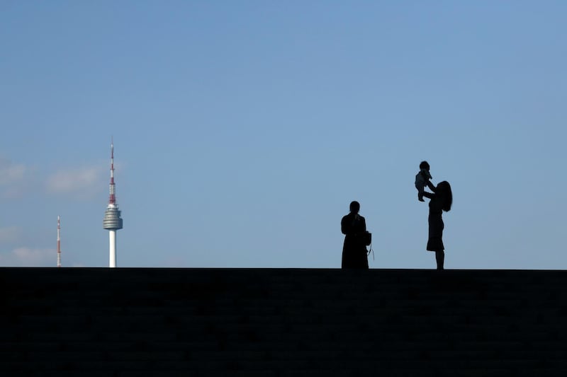 A mother holding up her baby is silhouetted against the backdrop of N Seoul Tower, commonly known as Namsan Tower, in Seoul, South Korea. Kim Hong-Ji/Reuters