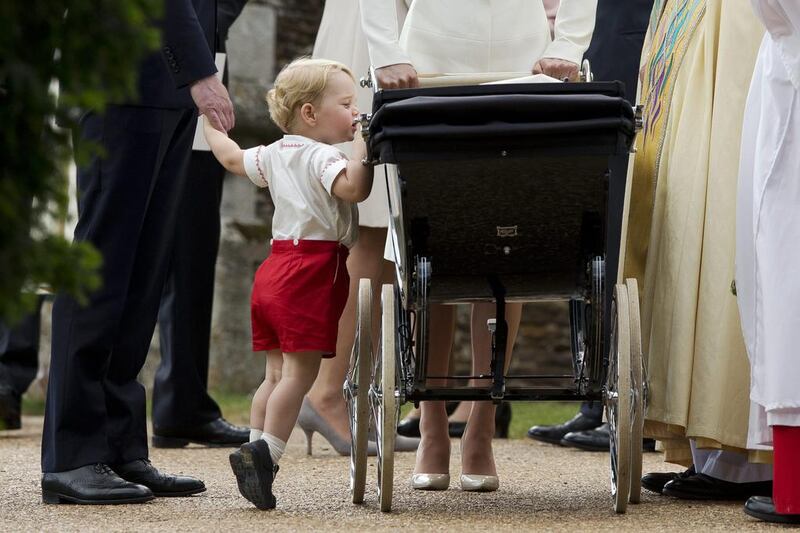 Britain’s Prince George gets up on tiptoes to peek into the pram of Princess Charlotte flanked by his parents Prince William and Kate the Duchess of Cambridge as they leave after Charlotte’s Christening at St Mary Magdalene Church in Sandringham, England. Britain’s royals on July 22, 2015 celebrate the second birthday of George, the first child of Prince William and his wife Kate.  Matt Dunham / AP photo