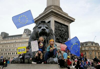 Demonstrators sit next to one of the lions in Trafalgar Square during a Peoples Vote anti-Brexit march in London, Saturday, March 23, 2019. The march, organized by the People's Vote campaign is calling for a final vote on any proposed Brexit deal. This week the EU has granted Britain's Prime Minister Theresa May a delay to the Brexit process. (AP Photo/Tim Ireland)