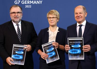 German Chancellor Olaf Scholz, right, holds up a written proposal to subsidise energy prices. Reuters 