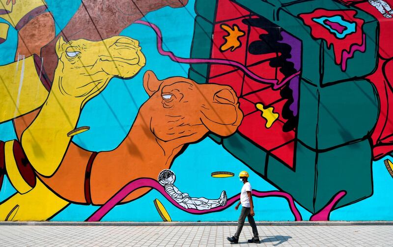 A worker wearing a hard hat walks past a mural in Dubai. Shopping malls in Dubai fully reopened for business on June 3.  AFP