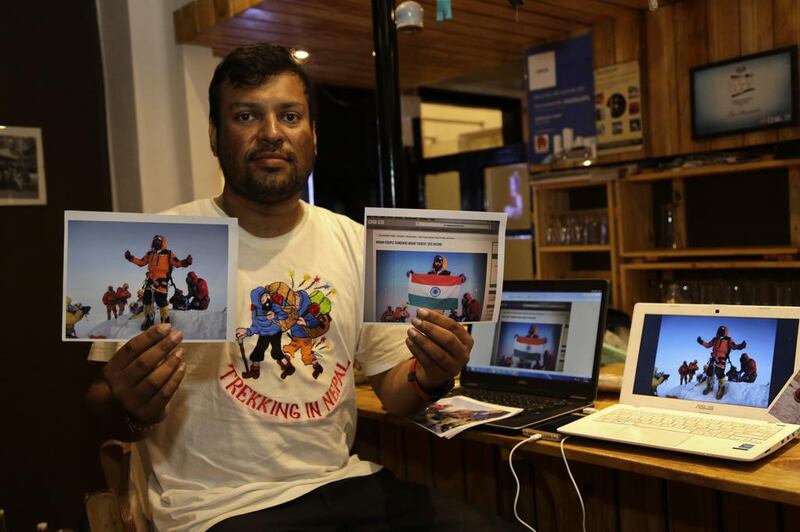 Indian climber Satyarup Sidhantha holds a photograph that shows him on Mount Everest, along with what he says is an altered version of the same used by a couple to make it appear they were on the summit. Bikas Das / AP