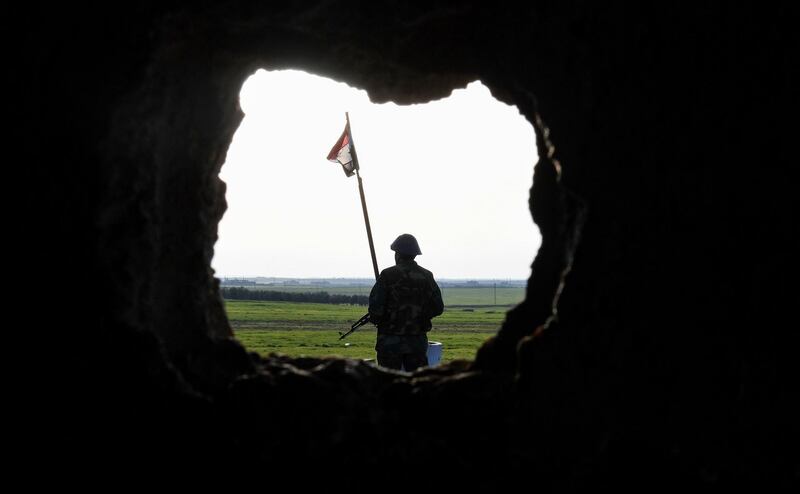 A Syrian soldier stands near a flag flying at a government forces' position in the village of Jubb Makhzoum, north west of the northern town of Manbij. AFP