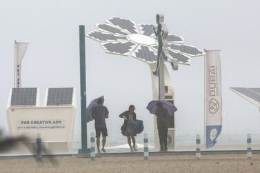 Beach-goers struggle with their umbrellas at Kite Beach, Dubai. Leslie Pableo / The National