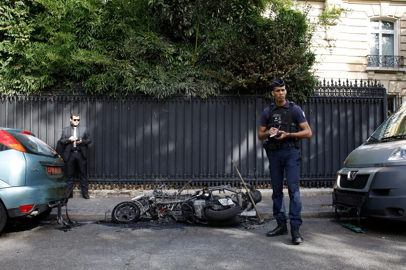 A police officer stands next to a burnt scooter outside the office of Jordan's military attache in Paris, Wednesday, Oct. 4, 2017. A police official told The Associated Press that the scooter caught fire Wednesday morning and caused a small explosion. The fire caused damage to a diplomatic vehicle and was extinguished. (AP Photo/Thibault Camus)