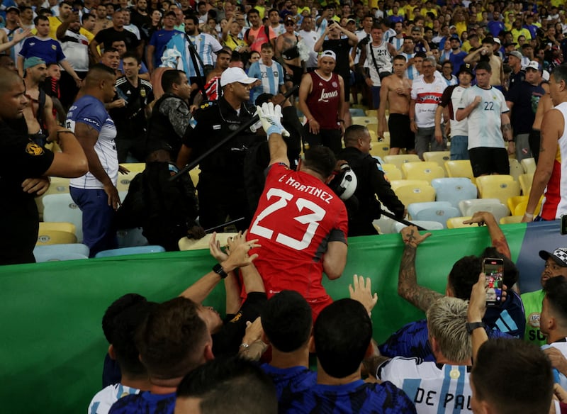 Emiliano Martinez reaches into the crowd in an attempt to calm the situation. Reuters