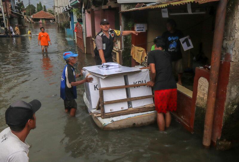 Workers transport ballot boxes through a flooded neighborhood in Banding, West Java.