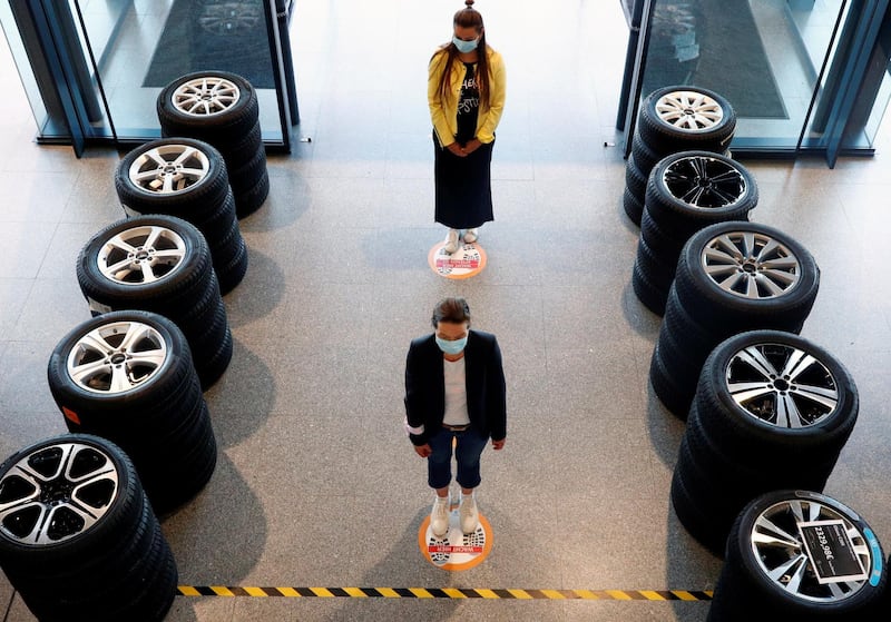 People stand on social-distancing markers at a Mercedes car dealer in Brussels, Belgium. REUTERS
