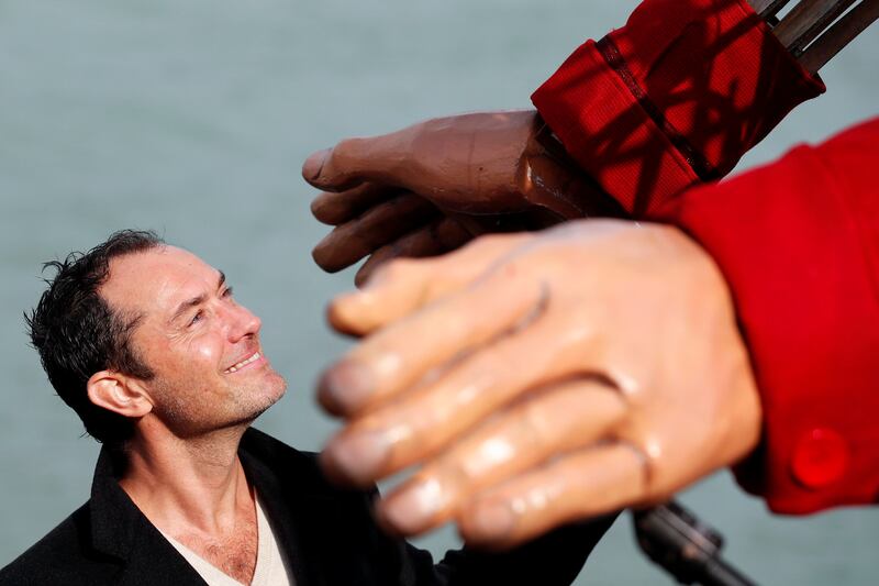 Actor Jude Law looks up at Little Amal after she arrived in Folkestone. Reuters