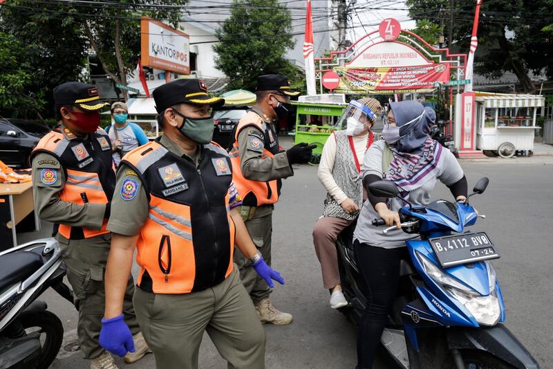 Traffic officers talk to motorists during a mask wearing and public health protocols campaign at a check point in Jakarta, Indonesia.  EPA