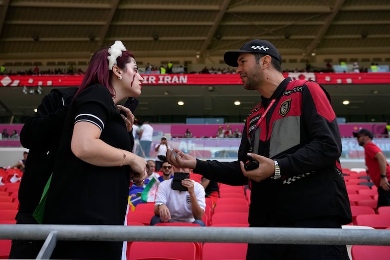 A security officer, right, interacts with an Iran supporter who displayed a shirt that read 'Mahsa Amini 22', in memory of the Iranian woman who died while in police custody in Iran. AP