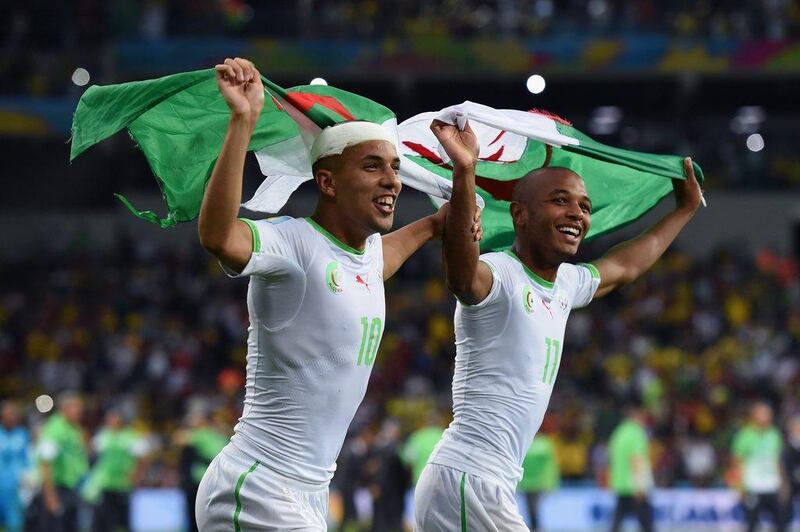 Sofiane Feghouli, left, and Yacine Brahimi celebrate with an Algerian flag after their 1-1 draw with Russia on Thursday night at the 2014 World Cupin Curitiba, Brazil. Matthias Hangst / Getty Images
