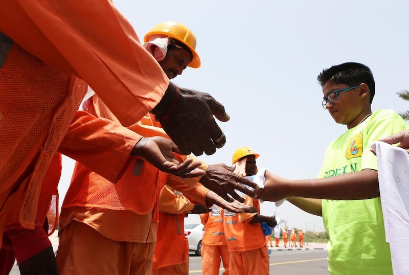 A young volunteer hands out water to workers in Dubai. Pawan Singh / The National