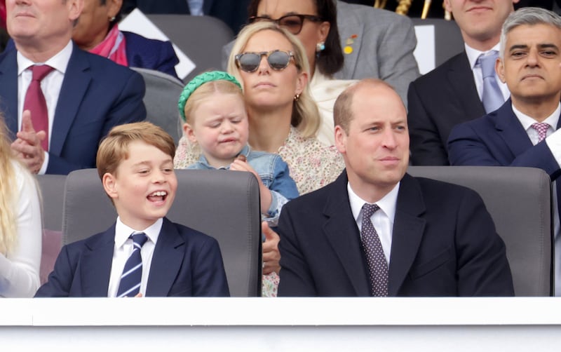 Zara Tindall wears a floral Zimmermann dress to the platinum jubilee pageant. Her daughter, Lena, is her lap. Prince George and Prince William sit in front. PA