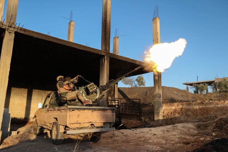 A fighter from the former al-Qaeda Syrian affiliate Hayat Tahrir al-Sham (HTS) fires an anti-aircraft gun mounted on a pickup truck in Syria's southern Idlib province on August 7, 2019. / AFP / Omar HAJ KADOUR
