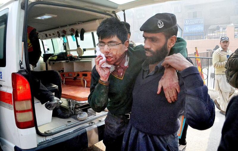 A hospital security guard helps a student injured in the shootout at a school under attack by Taliban gunmen in Peshawar, Pakistan on Tuesday, December 16. Taliban gunmen stormed a military school in the northwestern Pakistani city, killing and wounding dozens, officials said, in the latest militant violence to hit the already troubled region. Mohammad Sajjad / AP