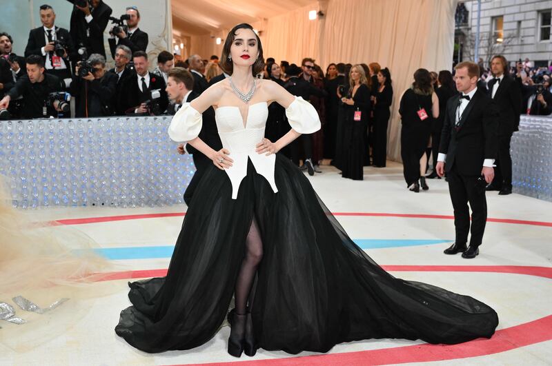 Lily Collins wears a black cape emblazoned with the word 'Karl'. AFP