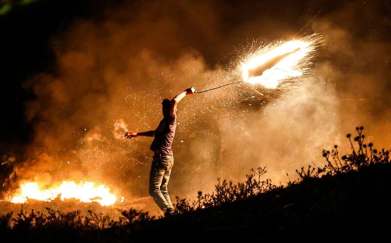 A Palestinian protester throws a burning projectile towards Israeli forces during a demonstration east of Gaza city in protest against the Israeli nationalist March of the Flags in Jerusalem's Old City, an event that celebrates the anniversary of Israel's 1967 occupation of East Jerusalem. AFP