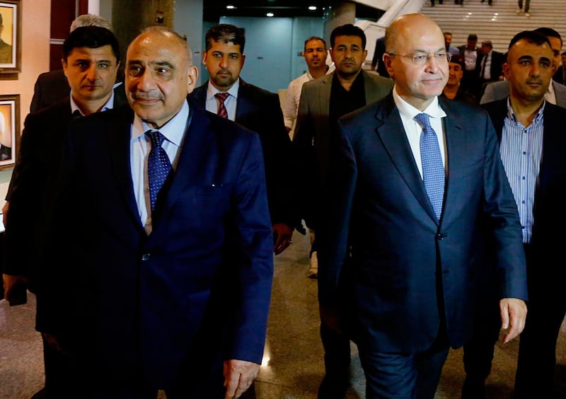 Iraq's new President Barham Salih, center right, walks with new Prime Minister Adel Abdul-Mahdi, center left, in the parliament building in Baghdad, Iraq, Tuesday, Oct. 2, 2018. Iraq's new president has tasked veteran Shiite politician Abdul-Mahdi with forming a new government nearly five months after national elections were held, state TV reported late Tuesday. (AP Photo/Karim Kadim)