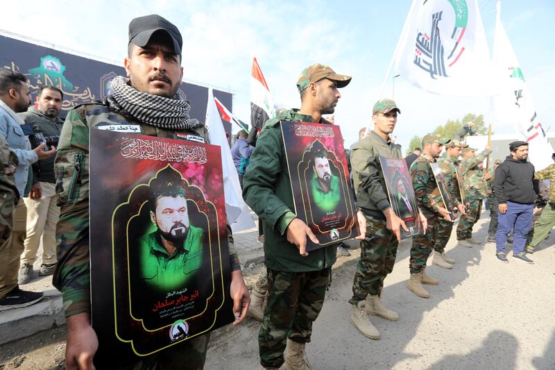 Members of the Popular Mobilisation Forces carry images of comrades who were killed in recent retaliatory US air strikes in western Iraq. EPA